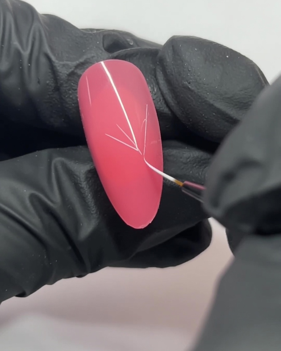 A close-up of a pink nail showing white lines intersecting to form a Y-shape guide.