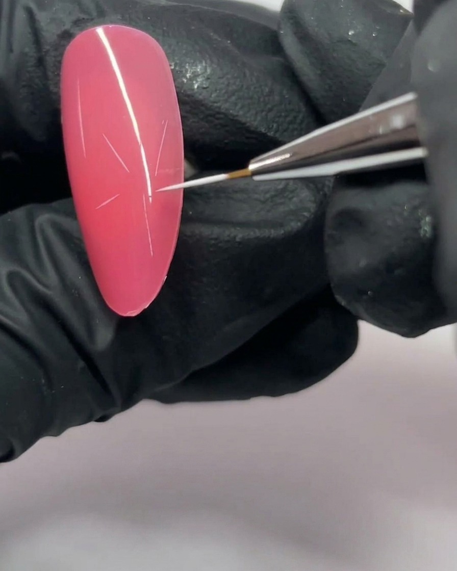 A close-up of a pink nail with a five-pointed star structure drawn in white.