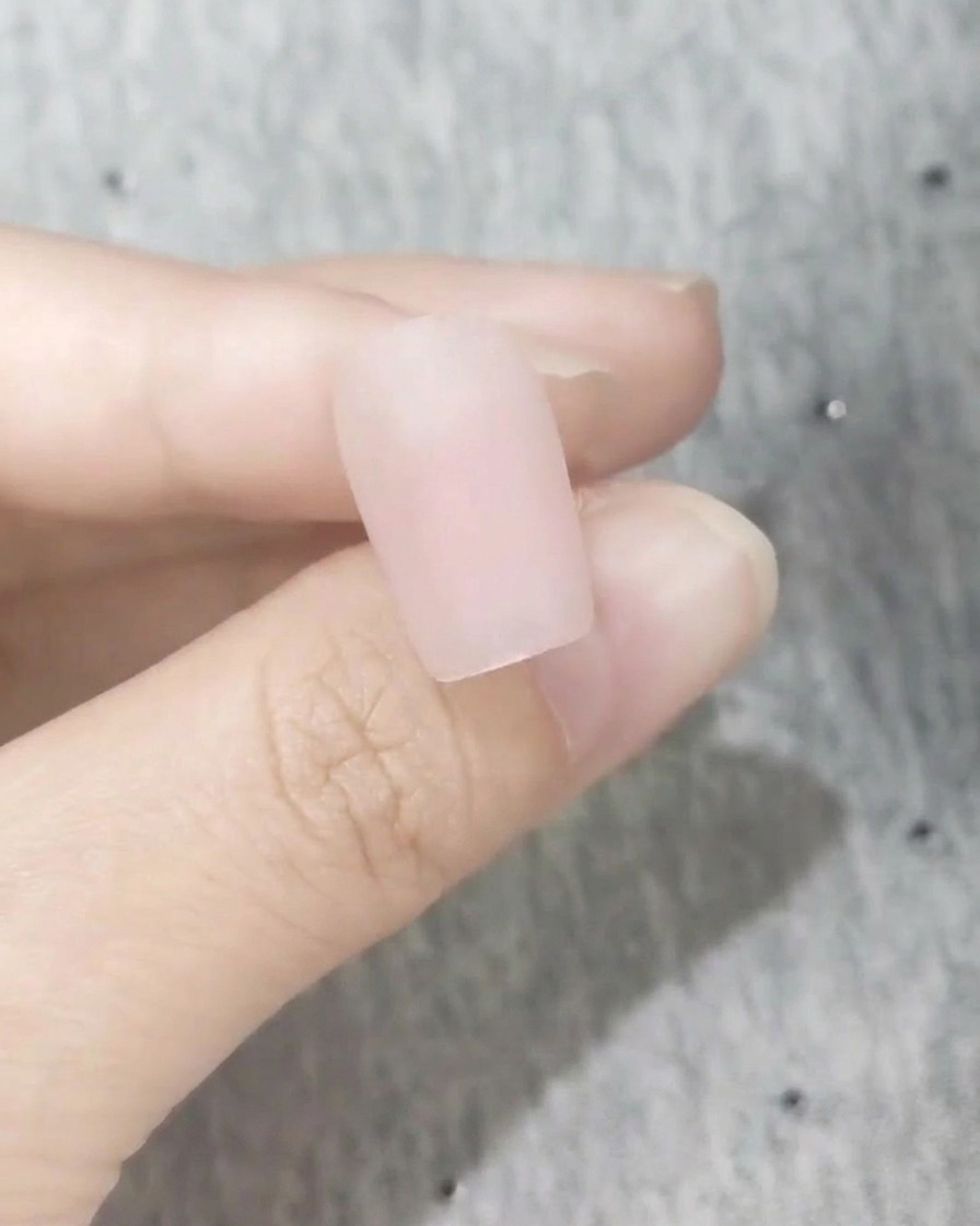 A close-up of a perfectly smooth nail with a frosted matte pink blush finish.