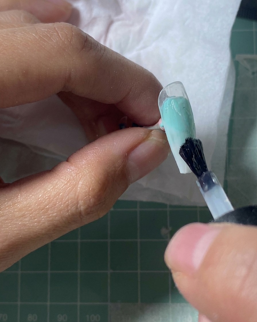 A nail tip resting under a UV lamp, with the surface appearing set and glossy.