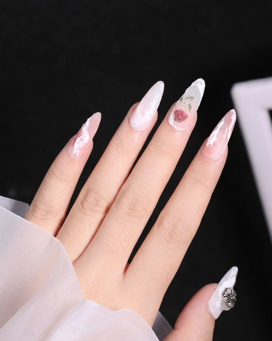A close-up shot of a fine liner brush applying white gel to form the top petal outlines of a rose on a manicured nail.