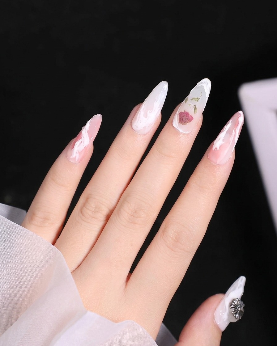A close-up view showing the lower petals being added to the white gel rose design on the nail.