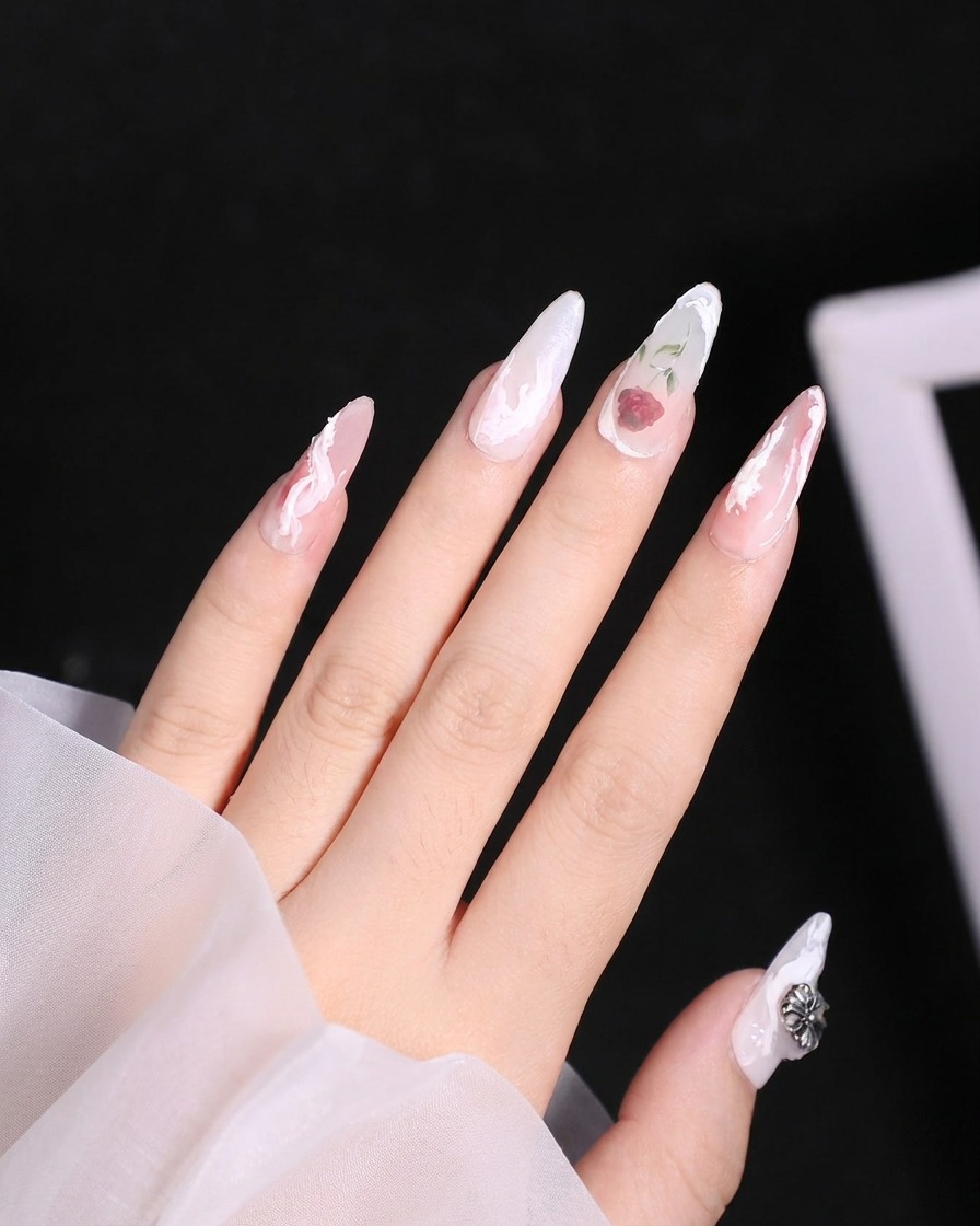 A brush blending the red color across the lower petals of a delicate rose design on a nail.