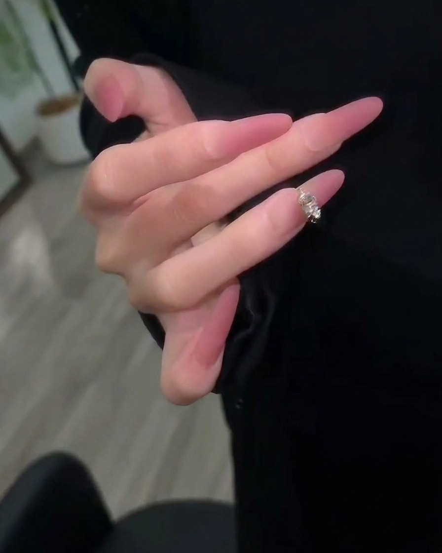 A thin layer of mauve gel polish being applied evenly to a nail.