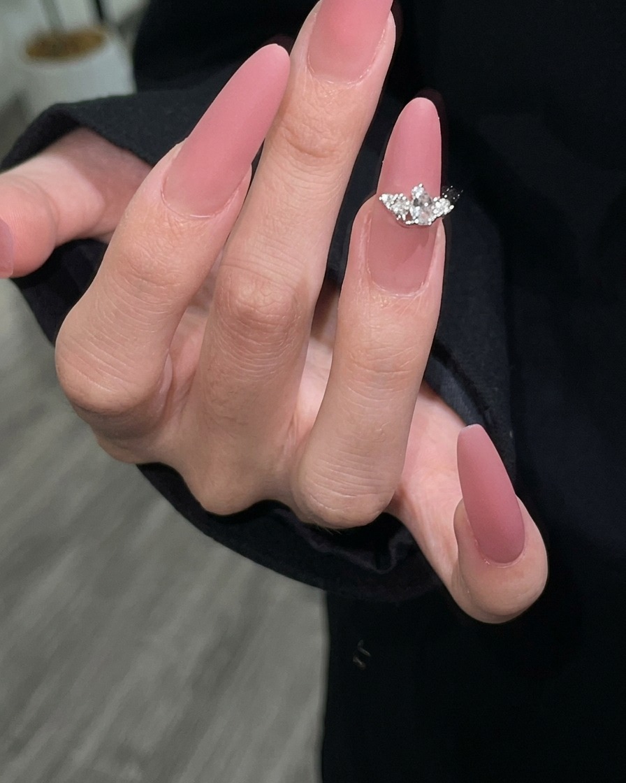 A second coat of mauve gel polish being applied to ensure complete coverage.