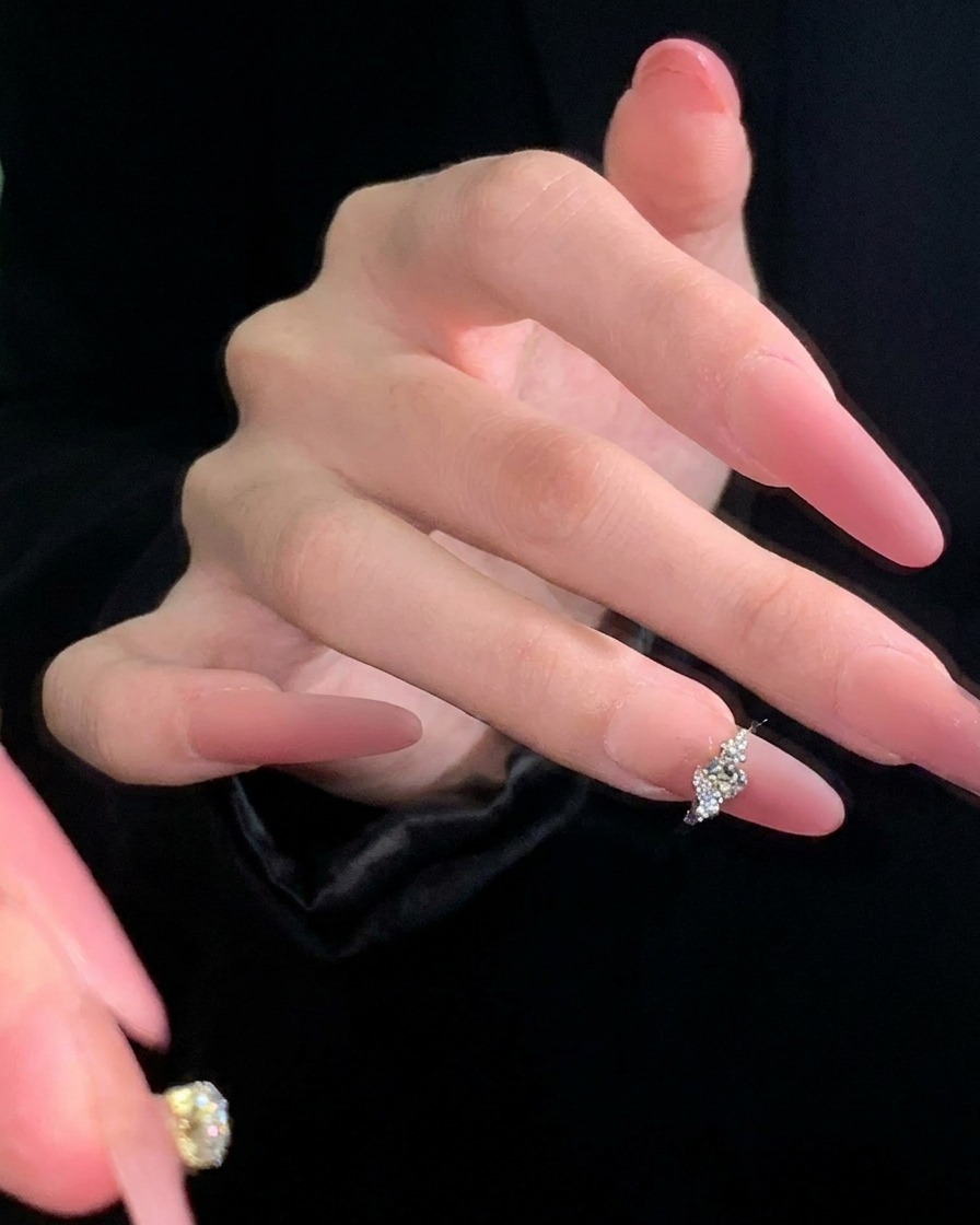 Tweezers carefully positioning a small silver butterfly-shaped charm onto the center of a mauve-colored nail.