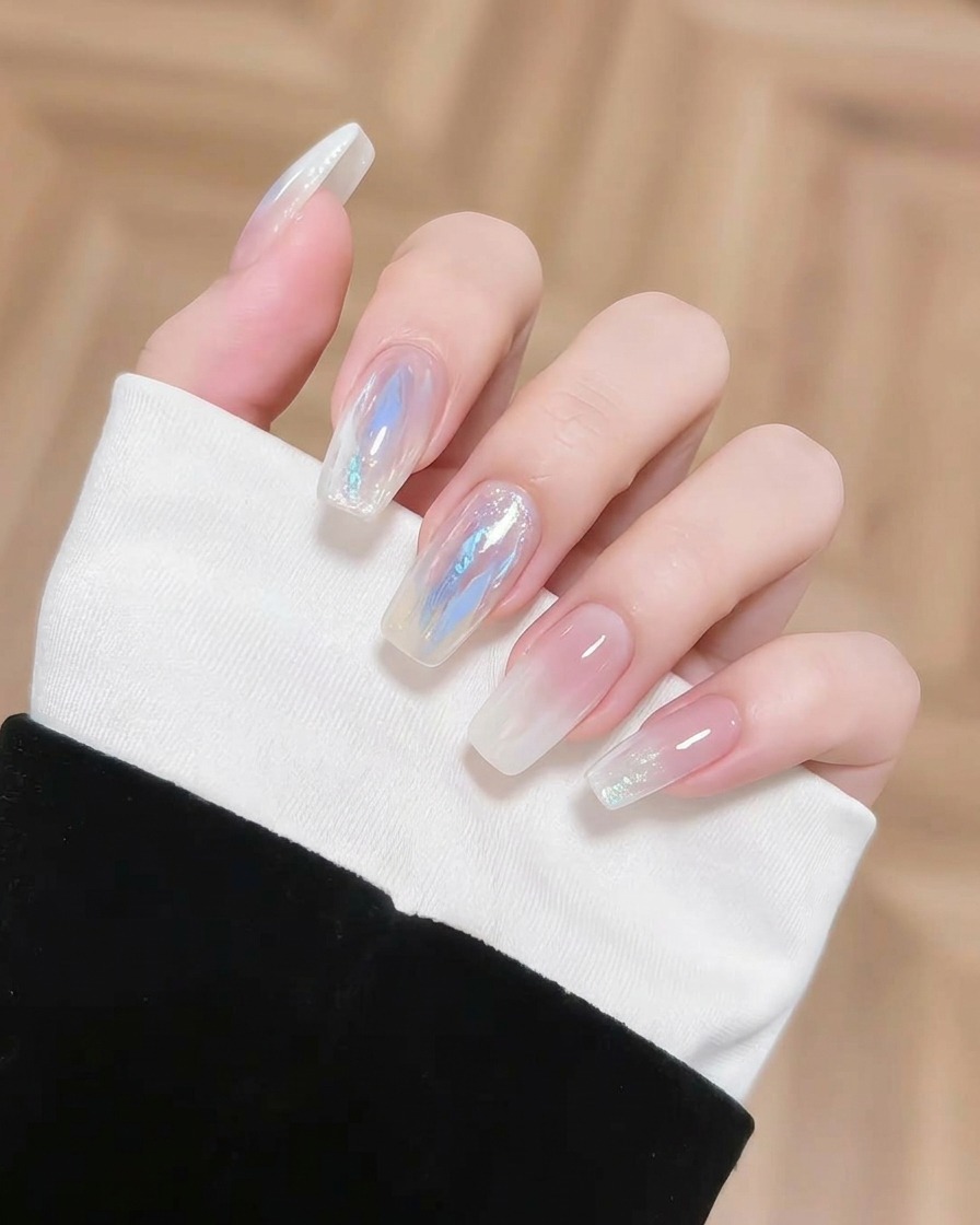 A small brush applying a concentrated dab of blue pigment onto a nail to add depth to the gradient.