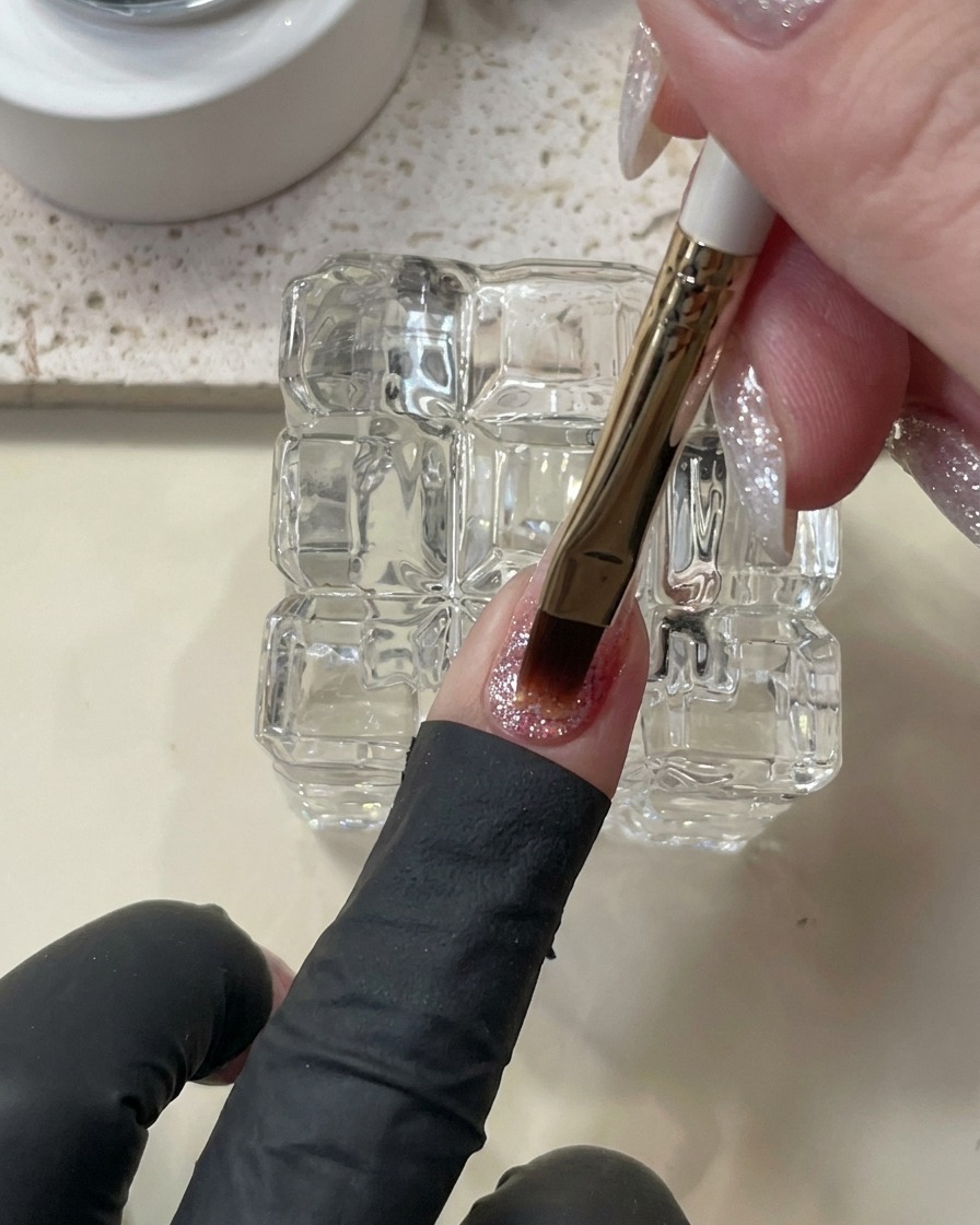 A brush applying a thicker, self-leveling bead of builder gel onto the nail.