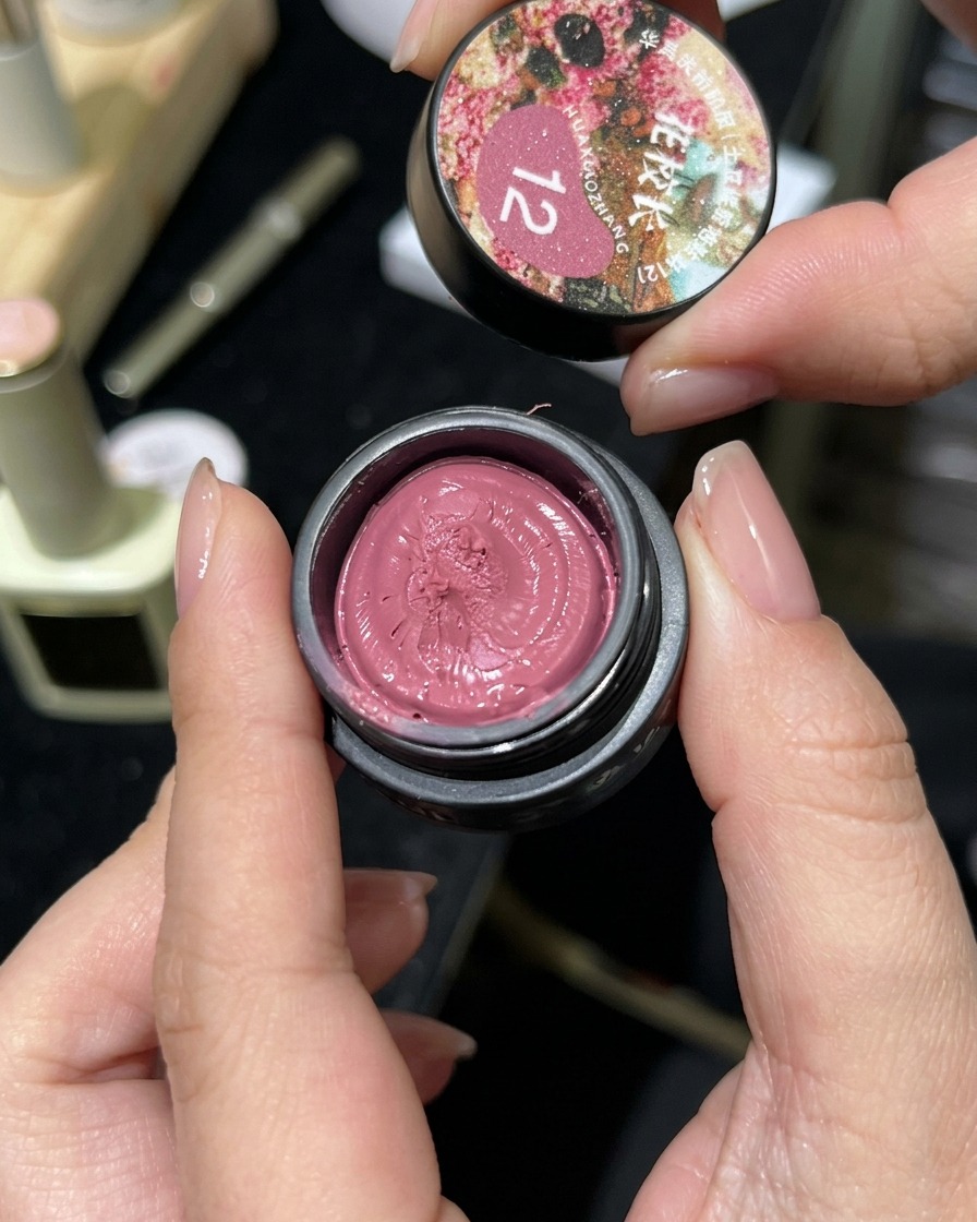 A small jar of pink cat-eye magnetic gel being opened, showing its clay-like texture.