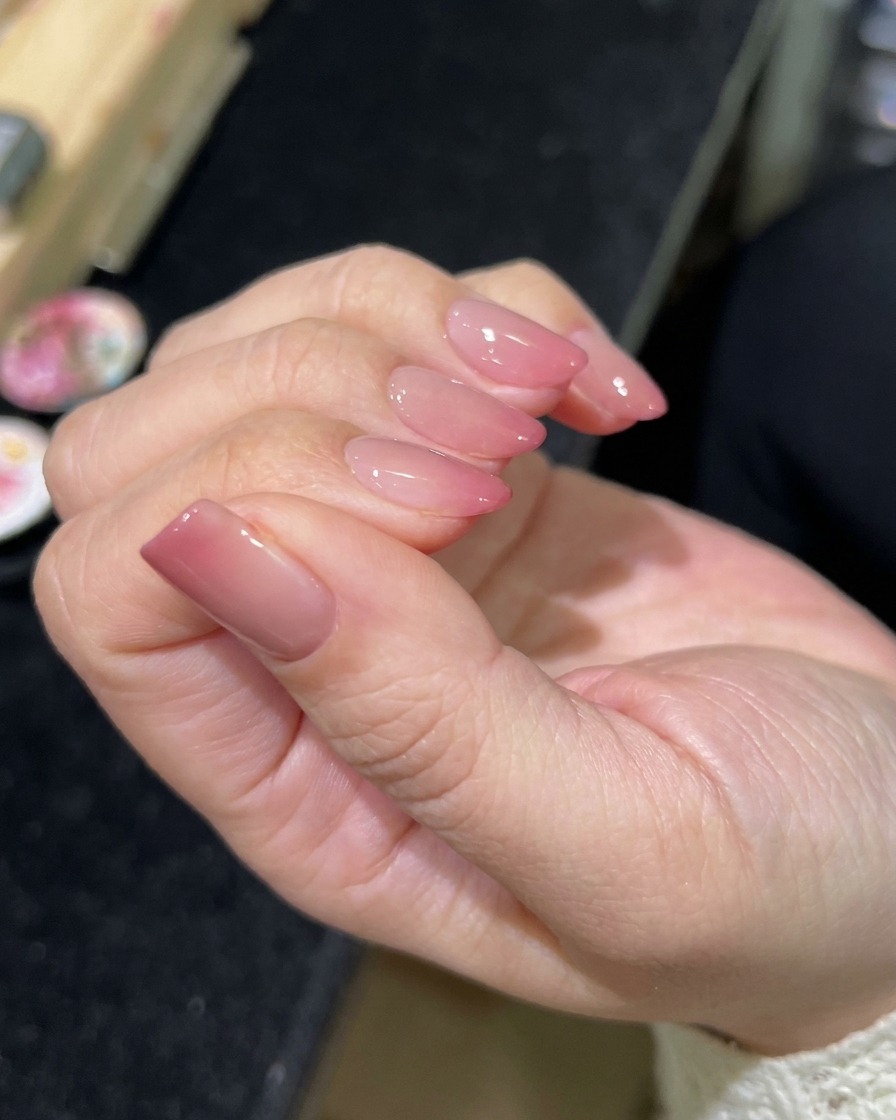 A brush applying a clear, glossy top coat over the finished magnetic nail art.