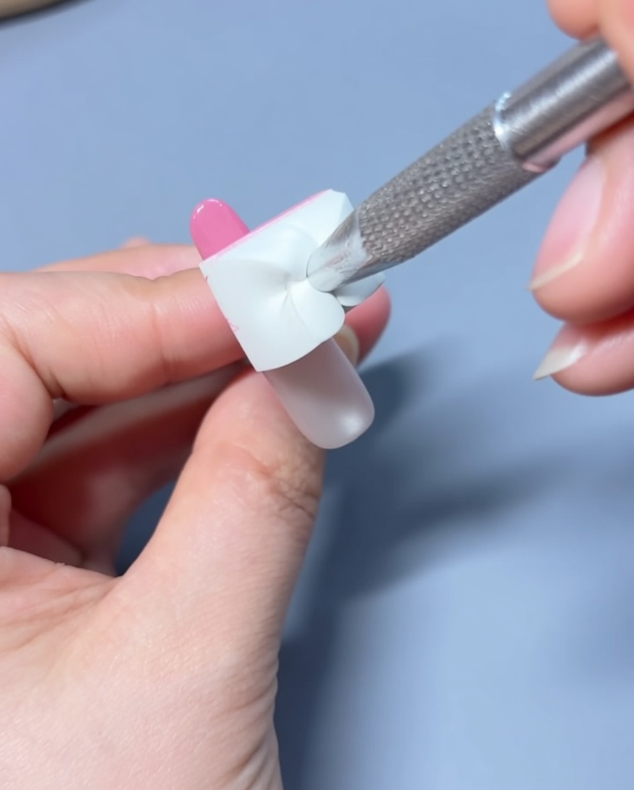 Applying a bead of pink gel polish to the tip of the prepared nail.