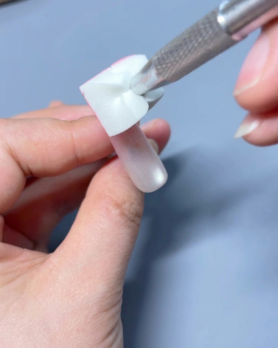 A flat gel brush softly blending the pink gel color into a gradient on the nail.