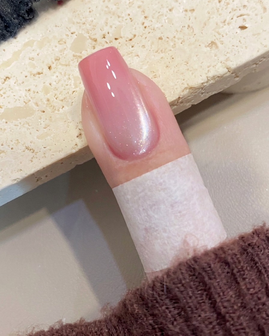 A magnetic tool held near the side of a nail, creating a diagonal shimmer line in the wet cat-eye gel.