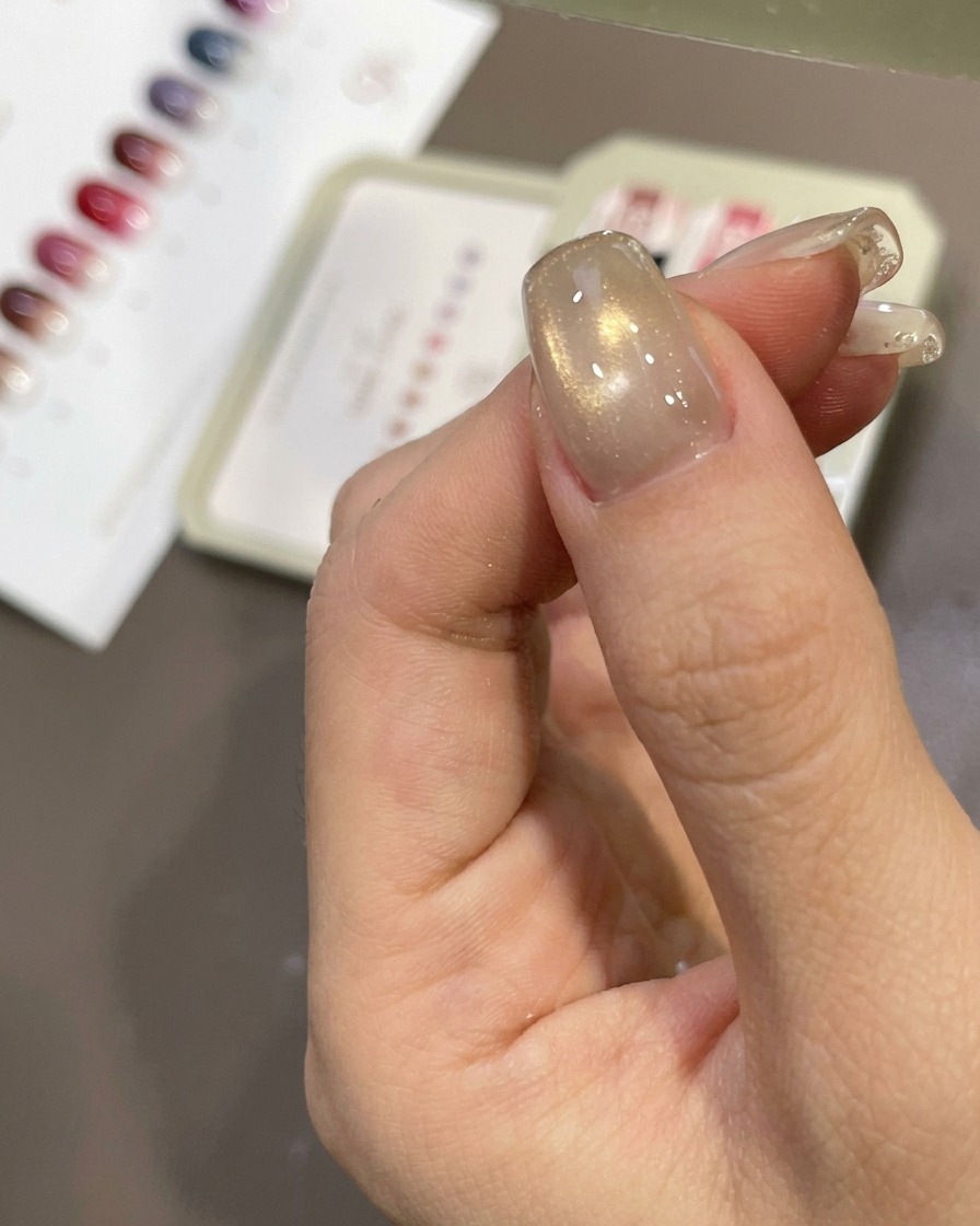 A nail being wiped with a lint-free wipe to remove the sticky layer.