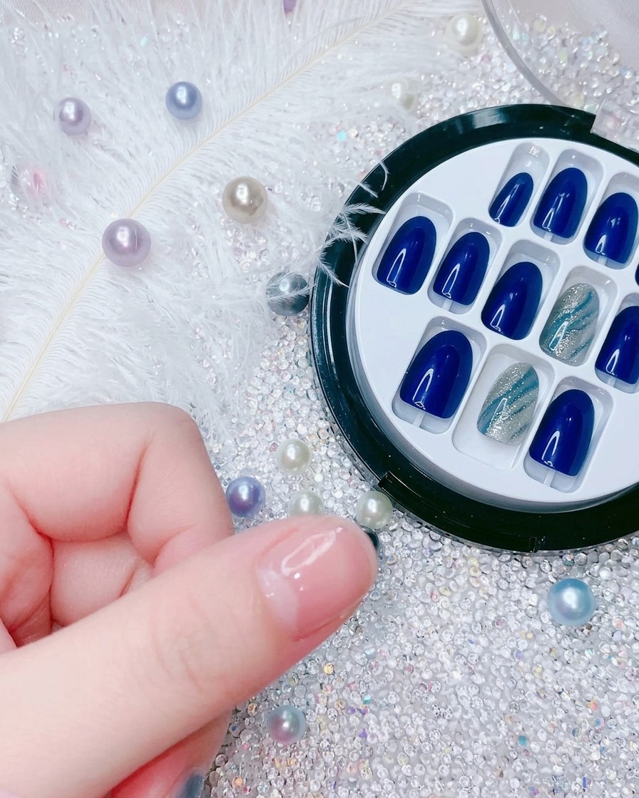 A close-up showing a hand positioning a new electric blue press-on nail over the index finger.