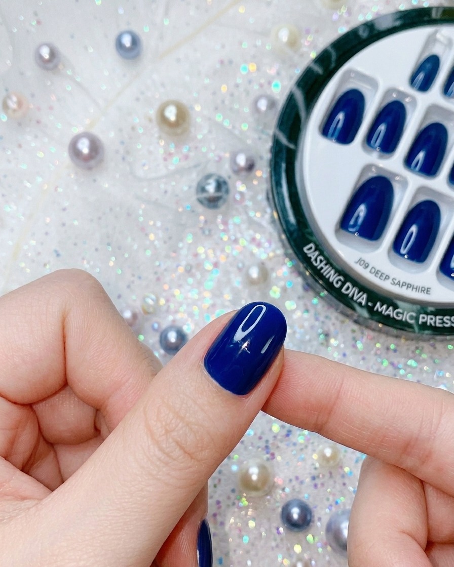 A close-up of a finger applying pressure to a deep blue press-on nail to finalize the adhesion.