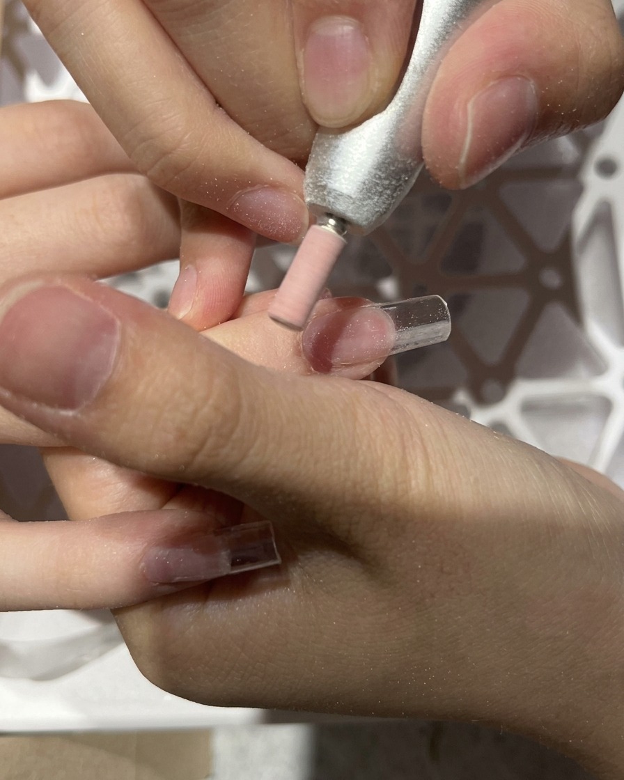 An e-file blending the junction between a plastic tip and the natural nail.