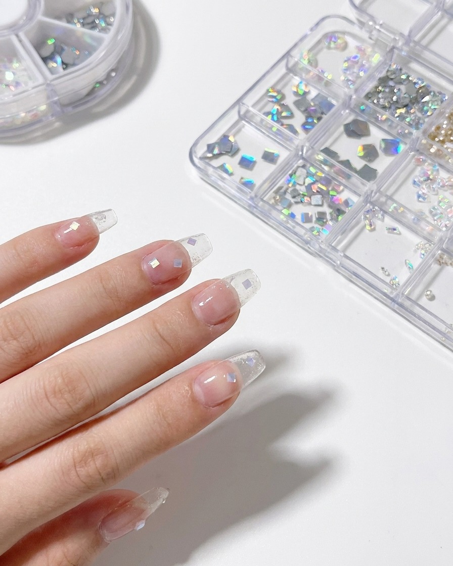 A dotting tool being used to meticulously place small, iridescent shell flakes onto a layer of wet gel.