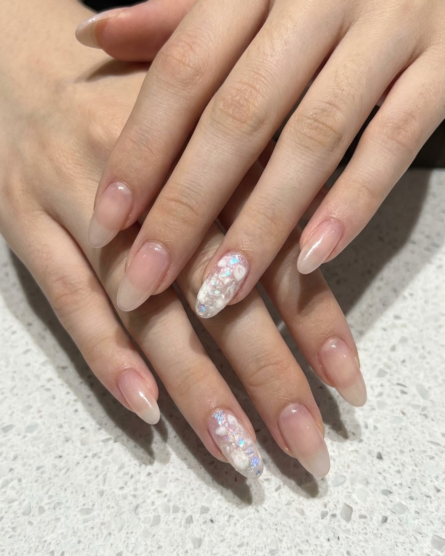 Close-up of a sponge applicator dabbing white gel onto a nude-pink manicured nail to build an ombre gradient.