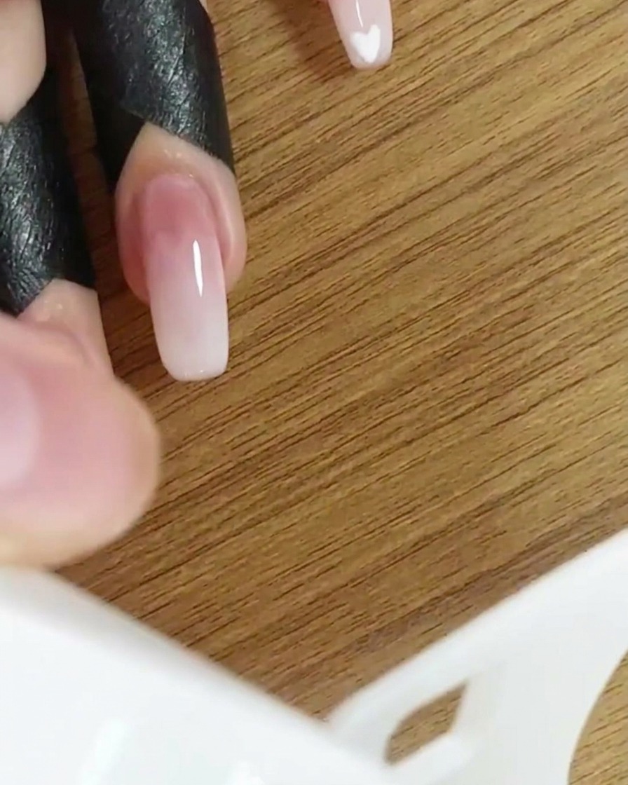 A hand inside a UV/LED nail lamp curing the gradient nail design.