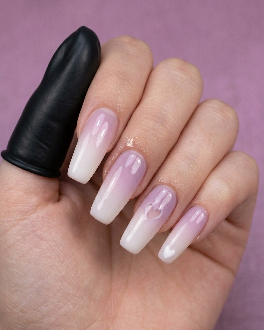 A close-up of a dotting tool creating a small white heart on a manicured nail.