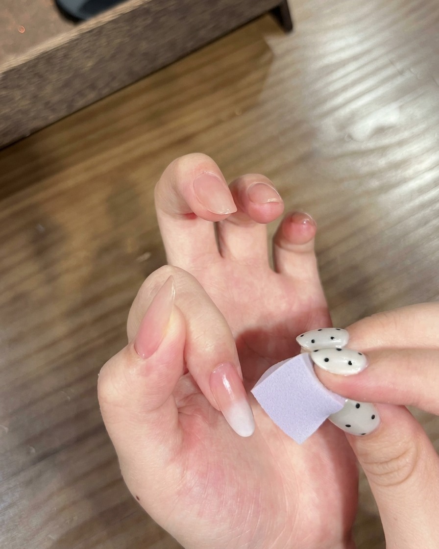 A hand with ombre nails being placed under a UV/LED lamp to cure the gradient.