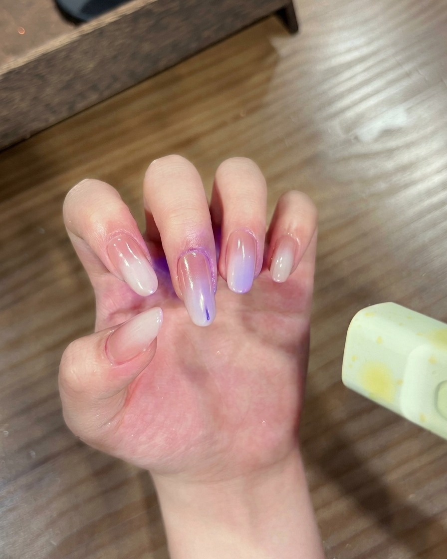 A hand with gradient chrome nails placed inside a UV/LED lamp for curing.