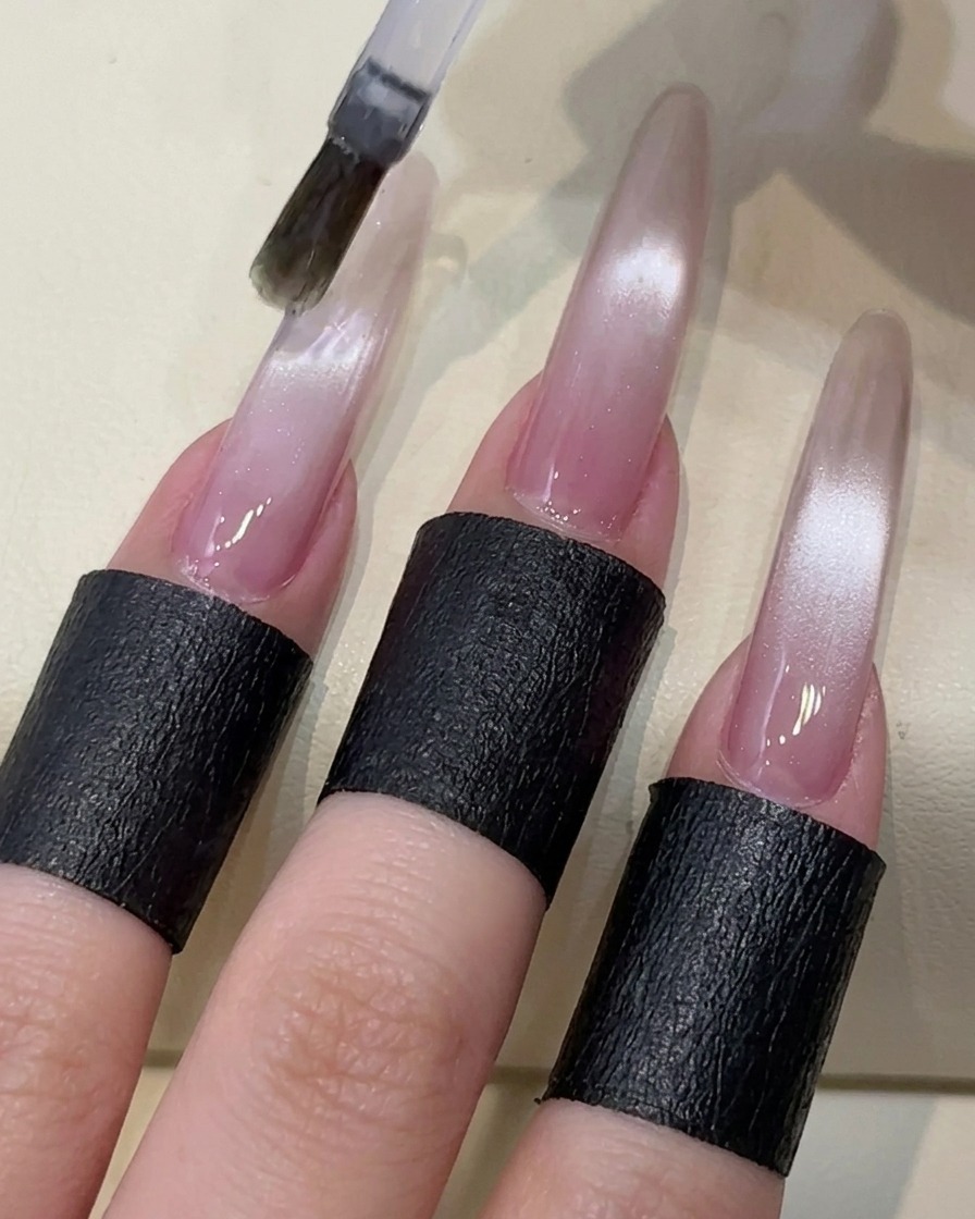 A brush applying a clear, non-wipe top coat over the cat-eye gel nail.