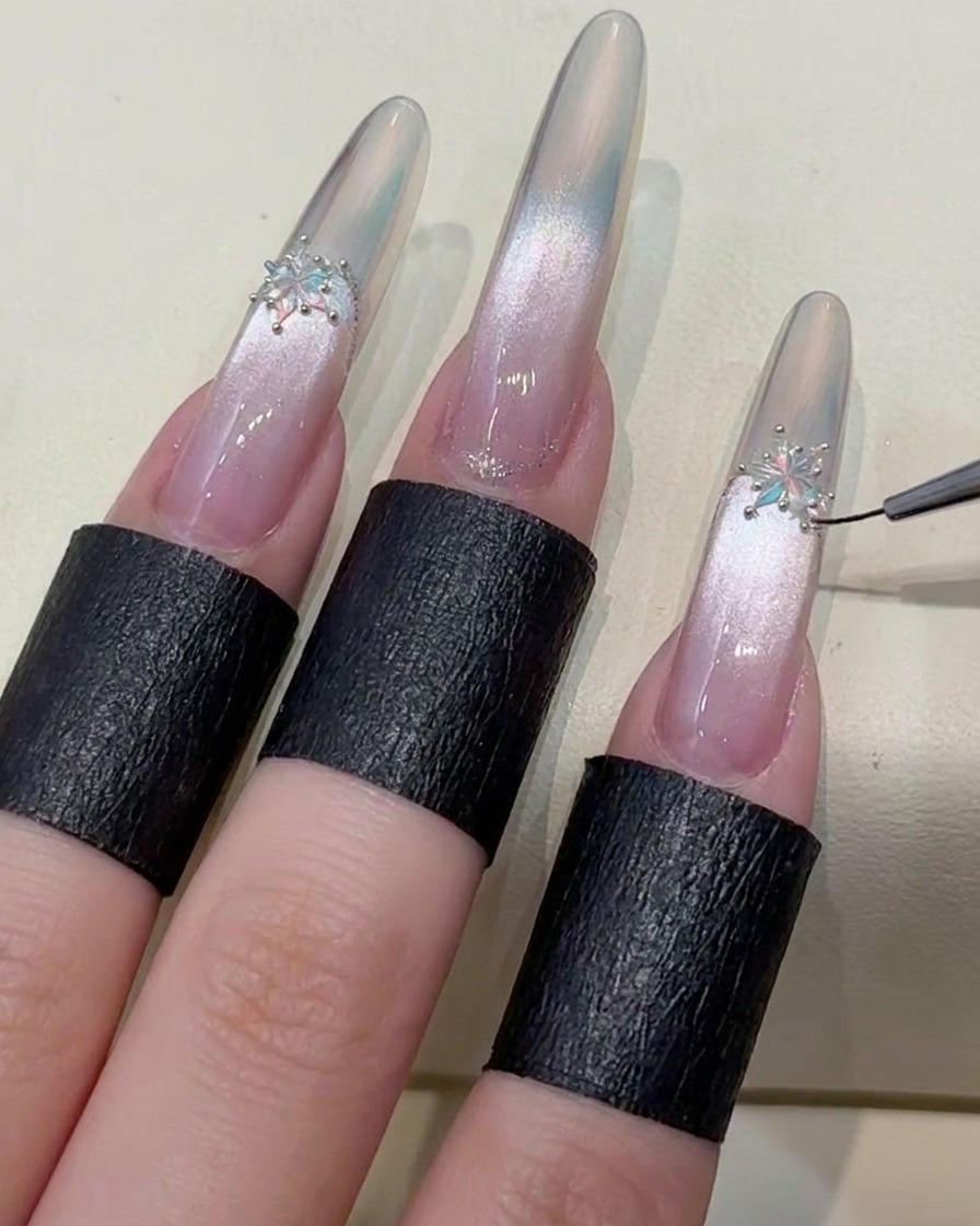 A brush applying a final hard-style top coat to seal the edges of the nail and the decorative crystals.