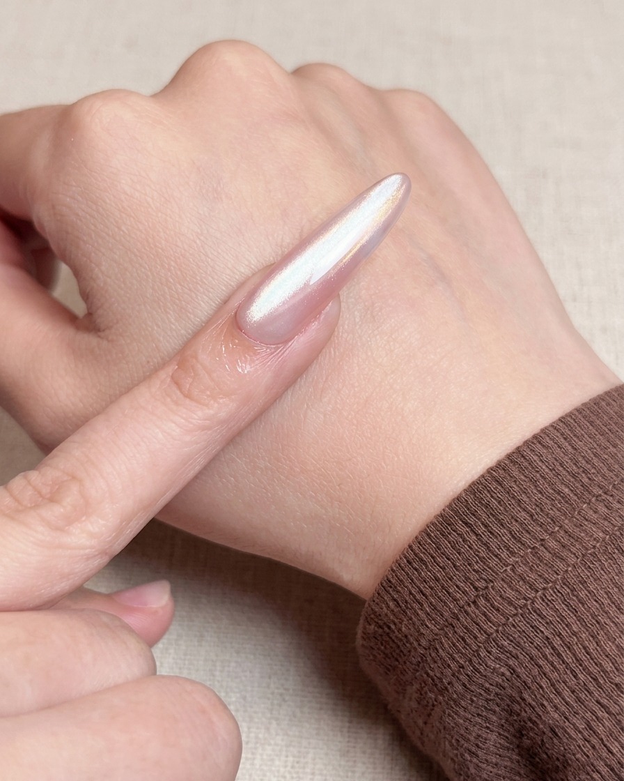 A close-up view of a brush applying a second coat of nude gel polish over the base layer, creating an opaque and smooth finish.