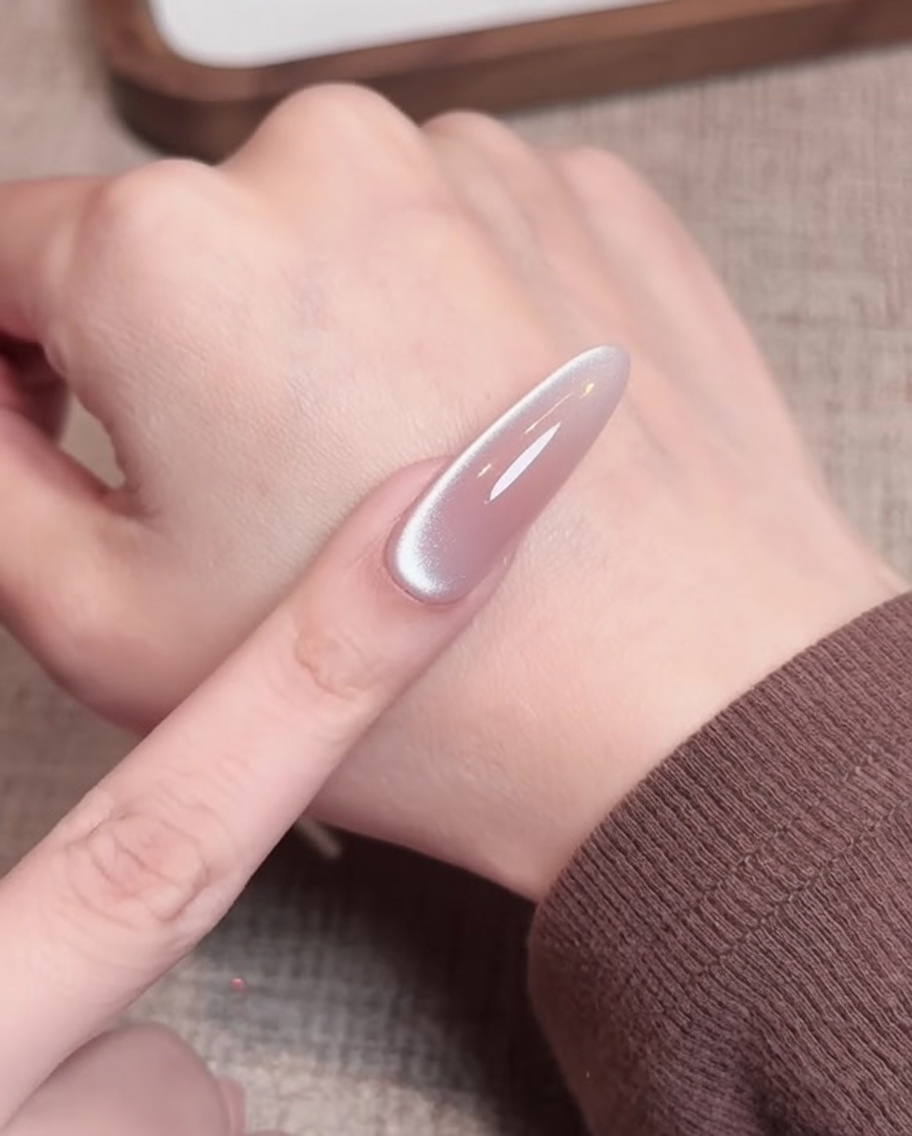 A lint-free wipe being used to clean the surface of a cured nude gel nail.