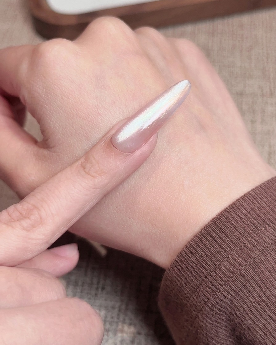 A nail brush applying a sheer pink top coat over a nail with a blush gradient, preparing it for the final cure.