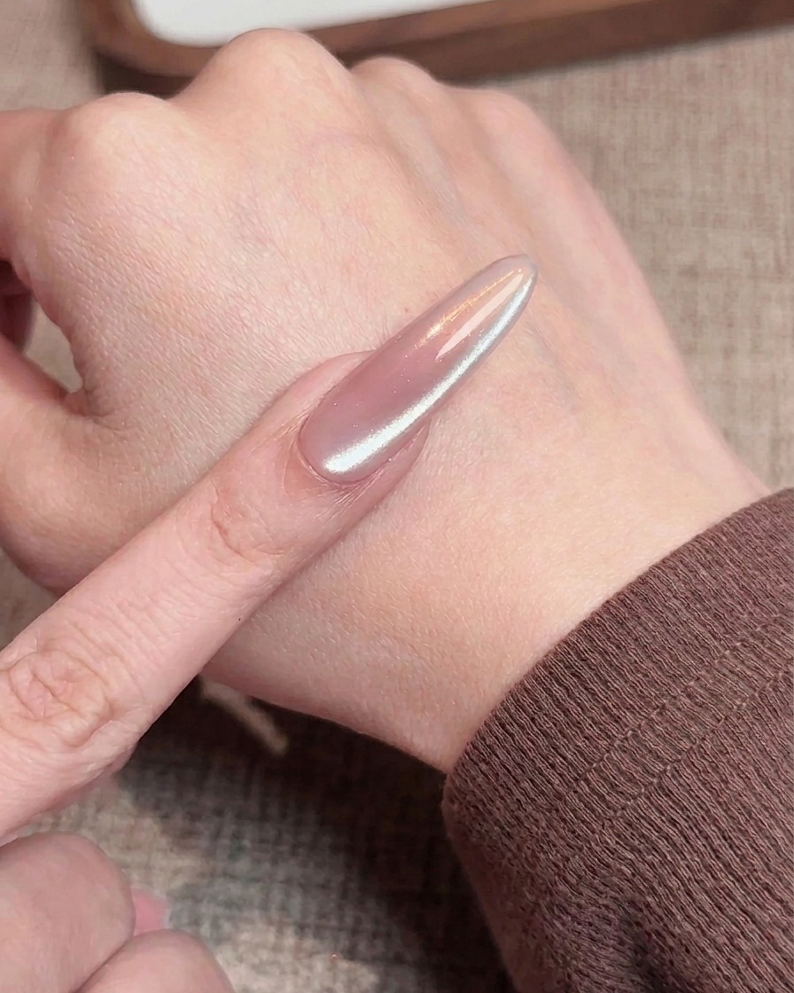 A close-up view of a buffing block lightly smoothing the free edge of a manicured nail.