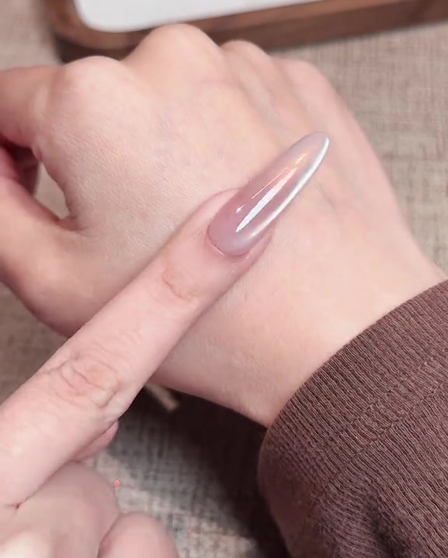 A magnet being held steadily beside a nail to pull the magnetic gel particles into a crisp, side-aligned reflective line.