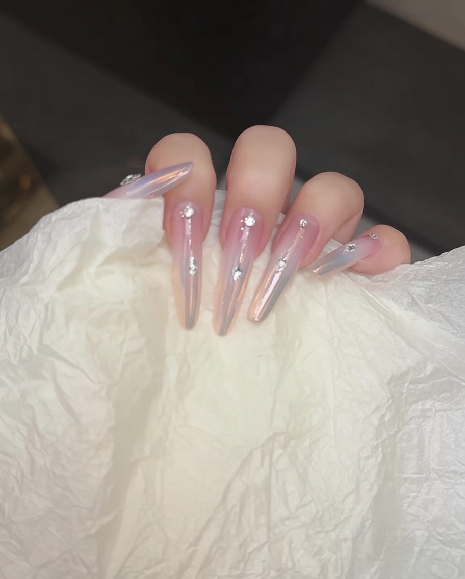 A brush applying a clear no-wipe top coat to the nail surface.