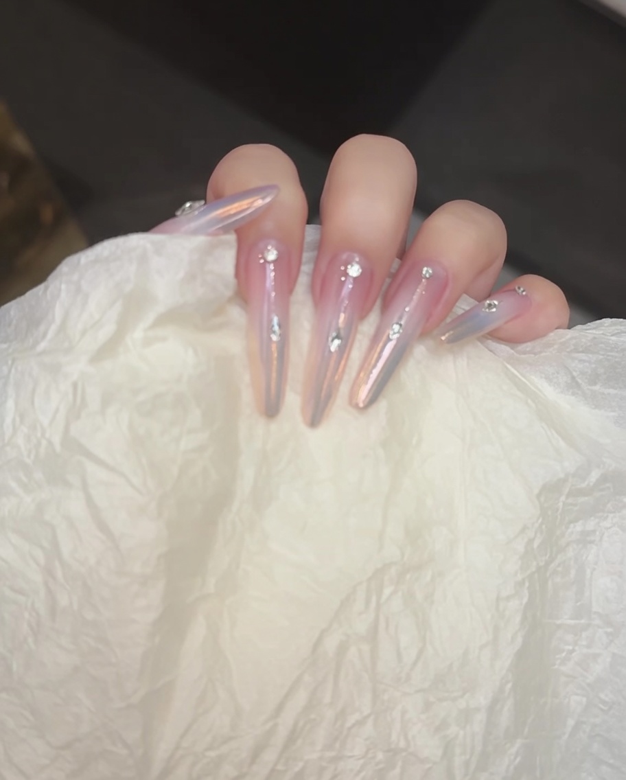 A thin detail brush painting a straight silver line down the center of a nail.