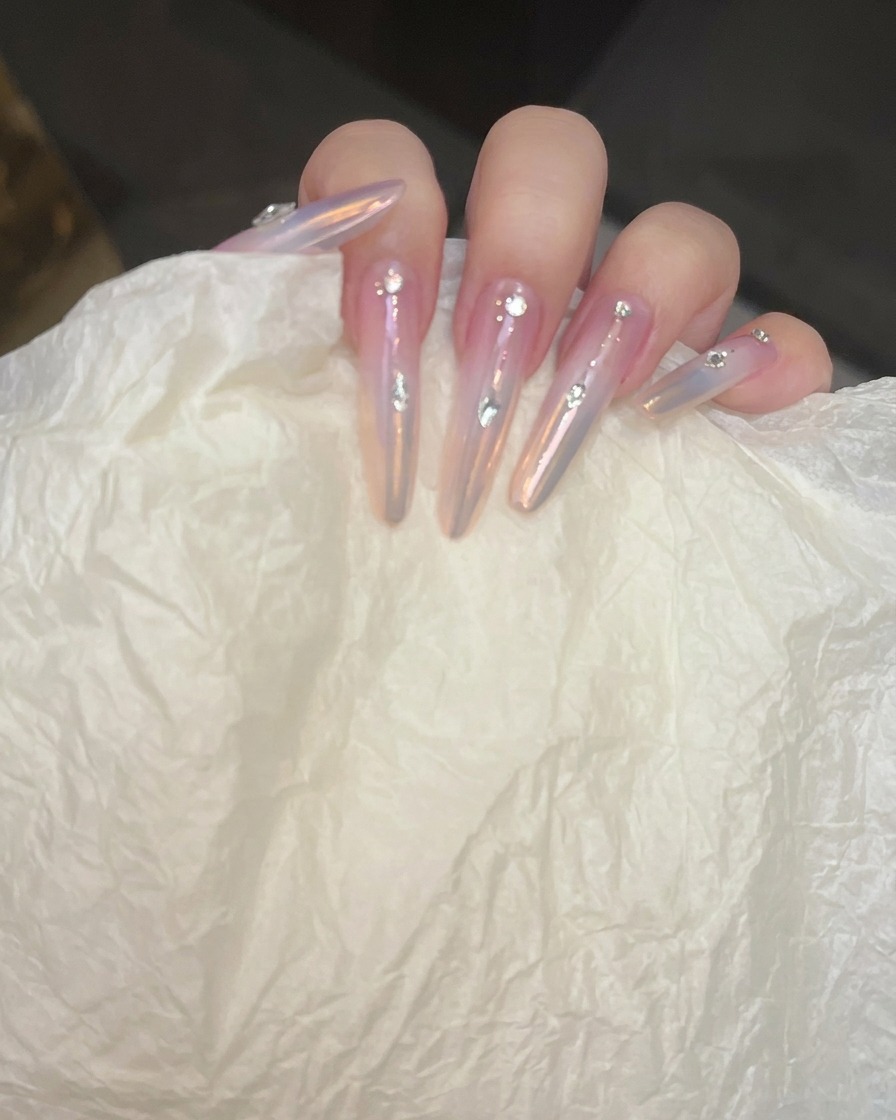 A close-up view of a nail where a thin silver line is being cleaned up with a detail brush.