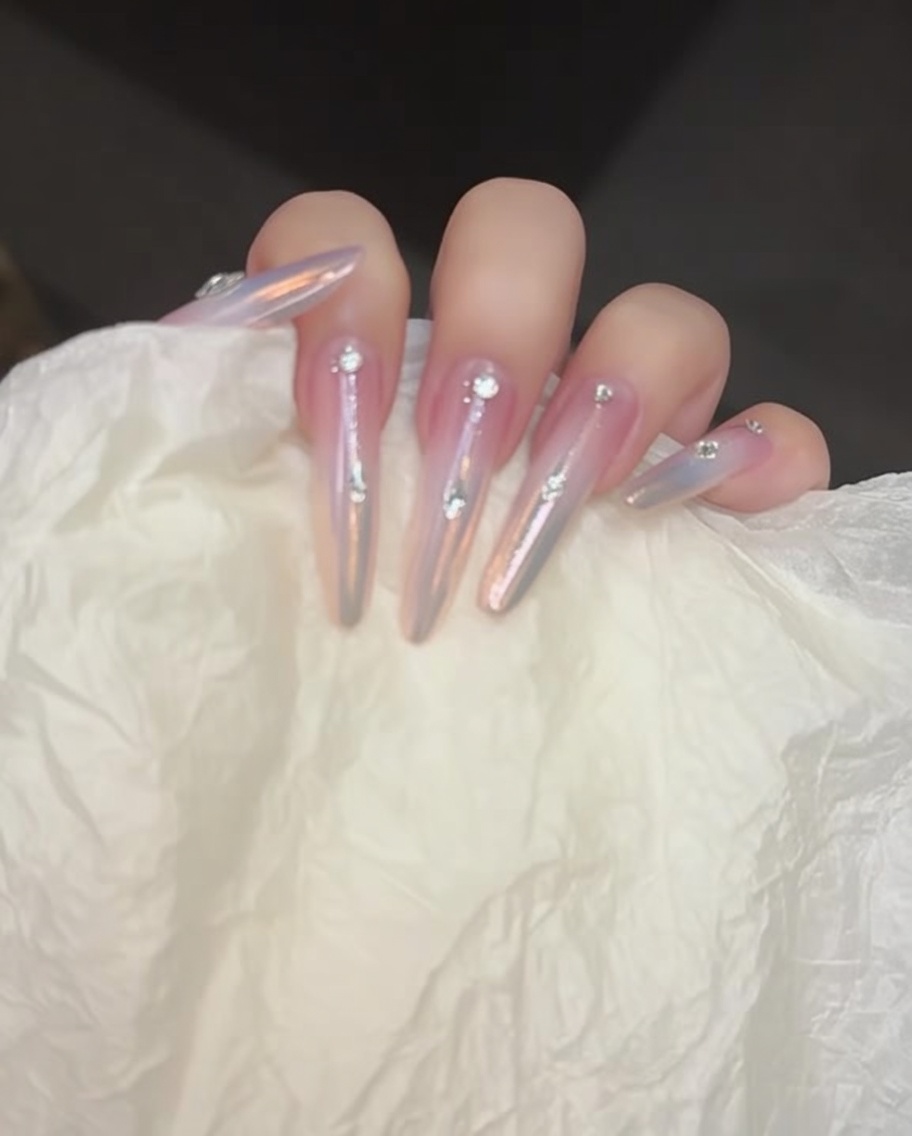 A crystal picker tool placing small rhinestones onto dots of adhesive gel on a manicured nail.