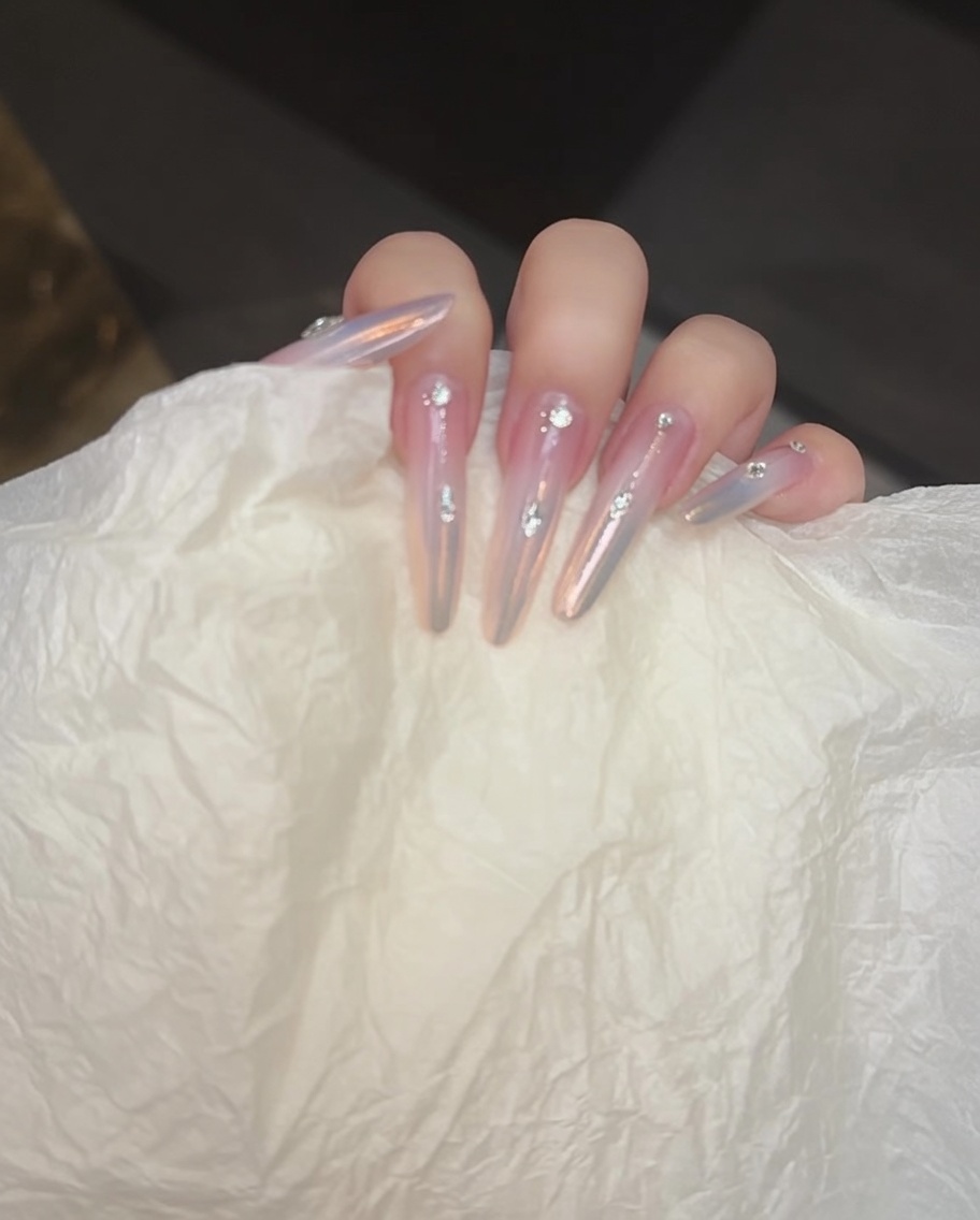 Applying a layer of clear hard gel over the nail surface and rhinestones to seal the final design.