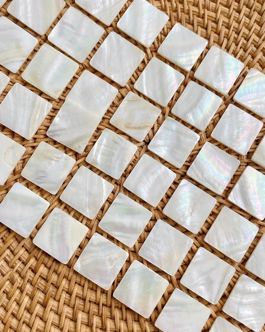 A close-up showing small, iridescent opal flakes being applied to a nail tip with tweezers.