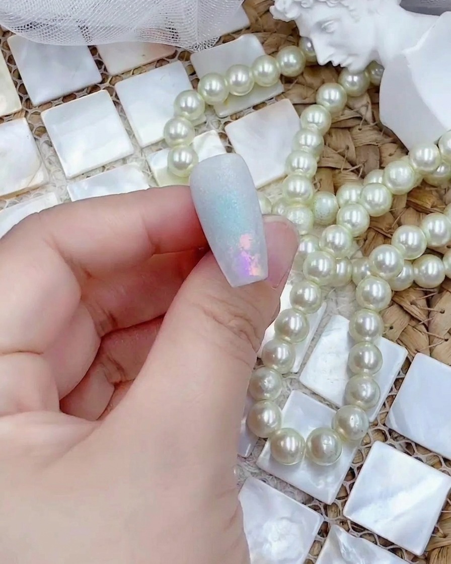 A nail tip being placed under a UV lamp after having a matte top coat applied.