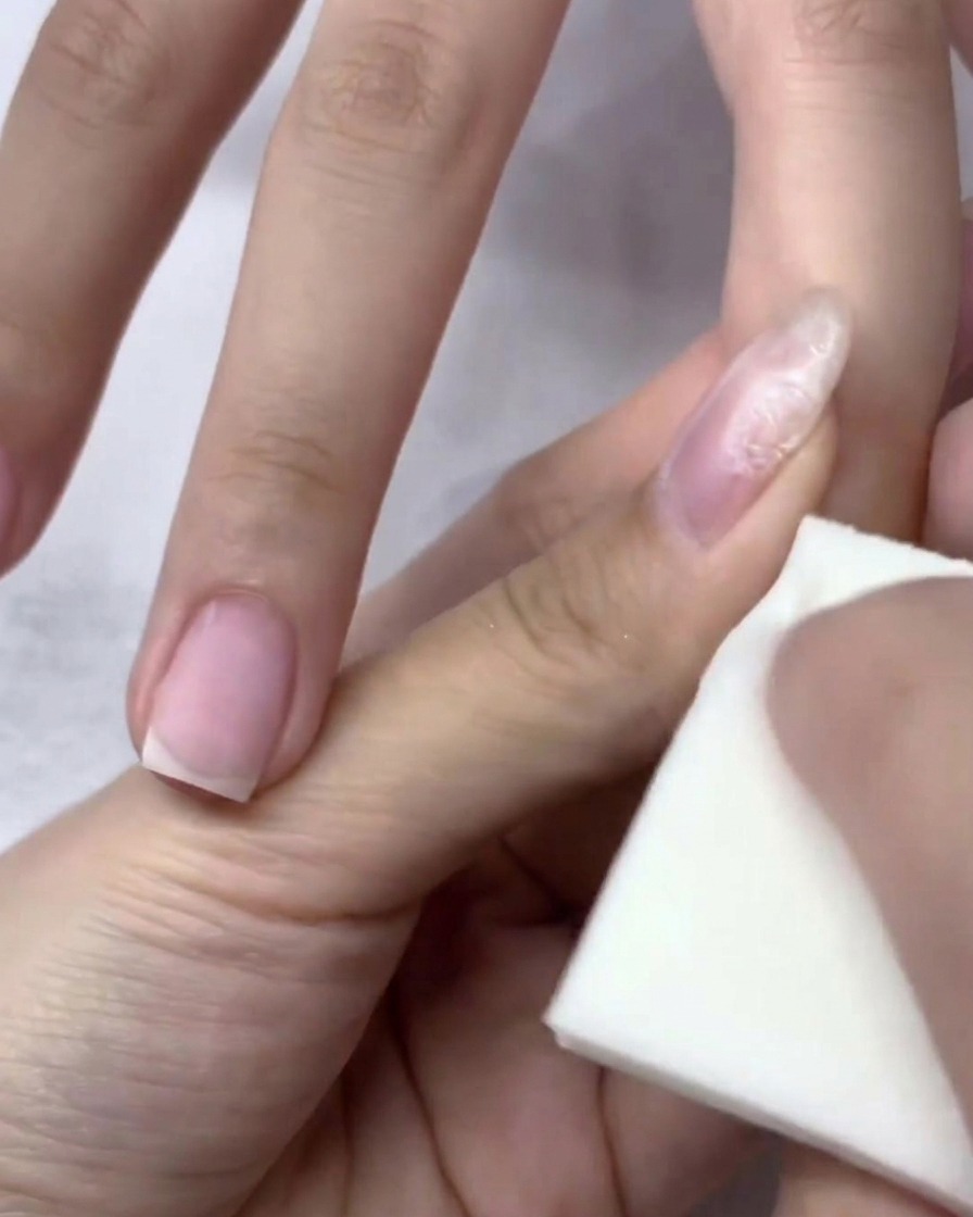 A close-up view of a hand inside a UV/LED nail lamp, with the nails under the light for the curing process.
