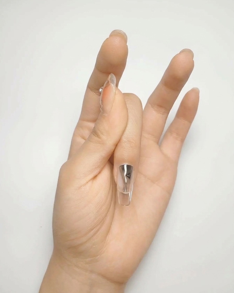 A close-up of a brush applying a second layer of nude gel polish, creating a smooth, opaque surface.