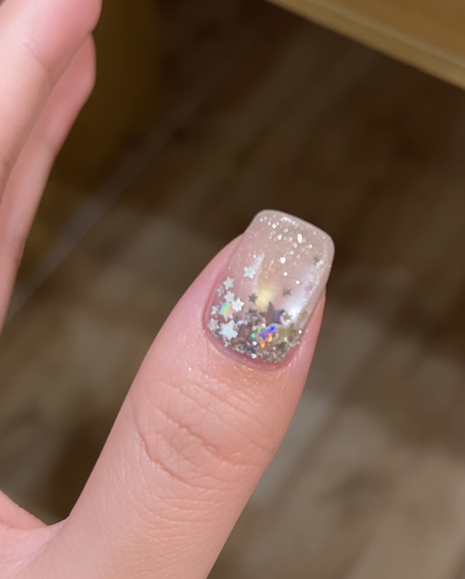 A brush applying a clear, viscous layer of builder gel over a cured cat-eye nail.