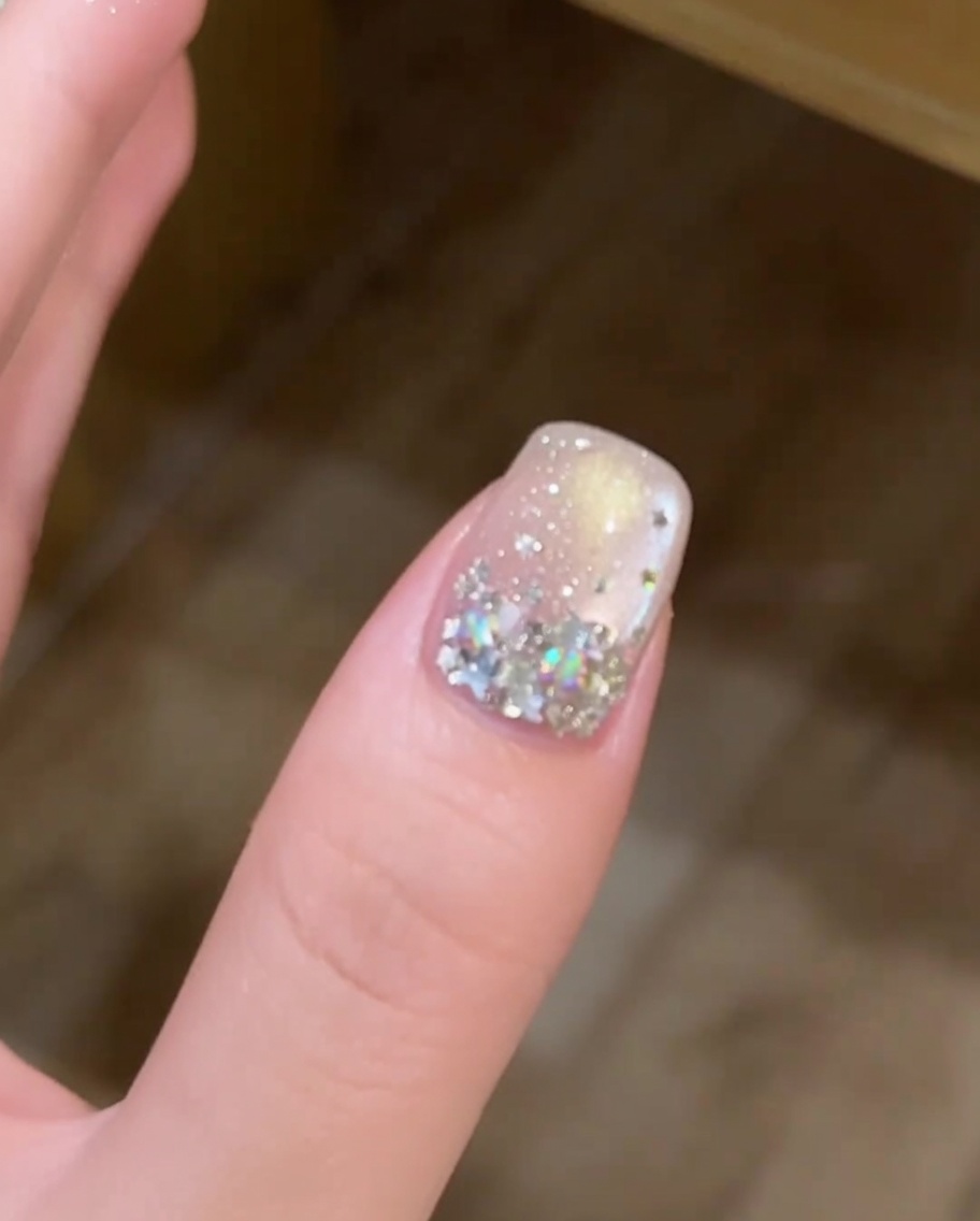 A hand positioned inside a professional nail lamp, with the decorated fingernail clearly visible under the UV light.