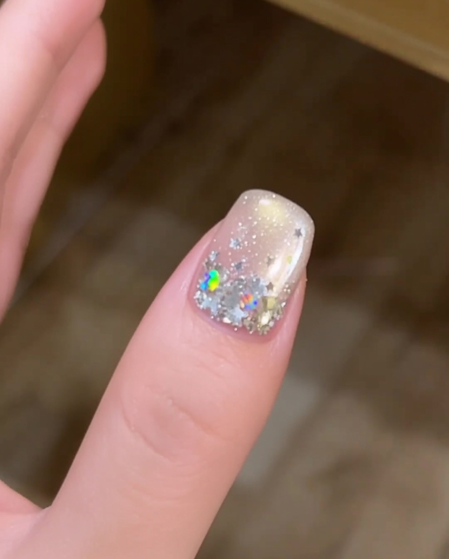 A close-up of a hand with star-decorated nails resting inside a UV lamp for curing.