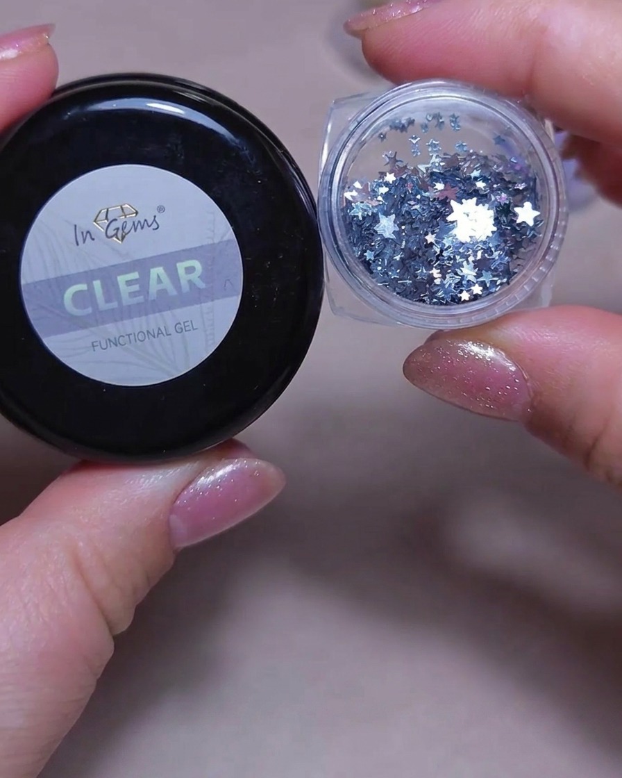 A small drop of clear builder gel being applied to the center of a manicured nail.