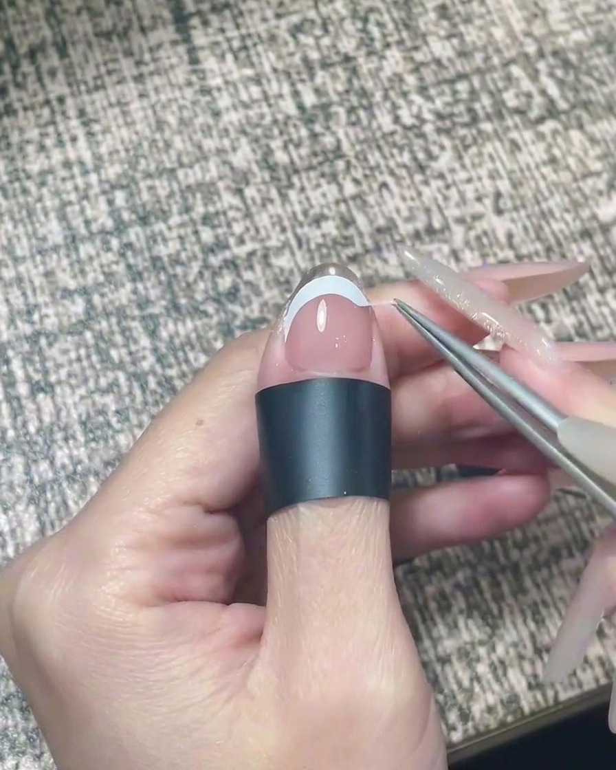A nail file gently buffing the free edge of a nail with applied silver chrome.