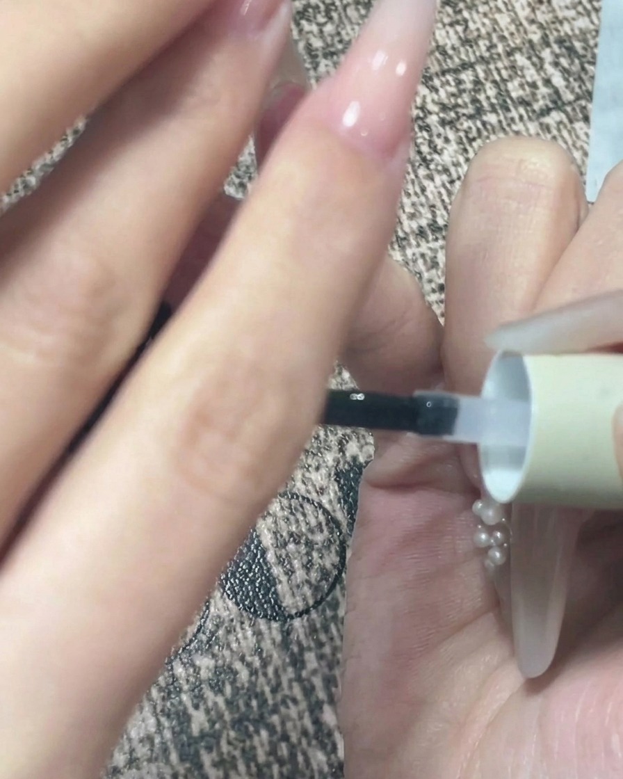 A close-up view of a hand being held upside down after top coat application to allow the gel to self-level.