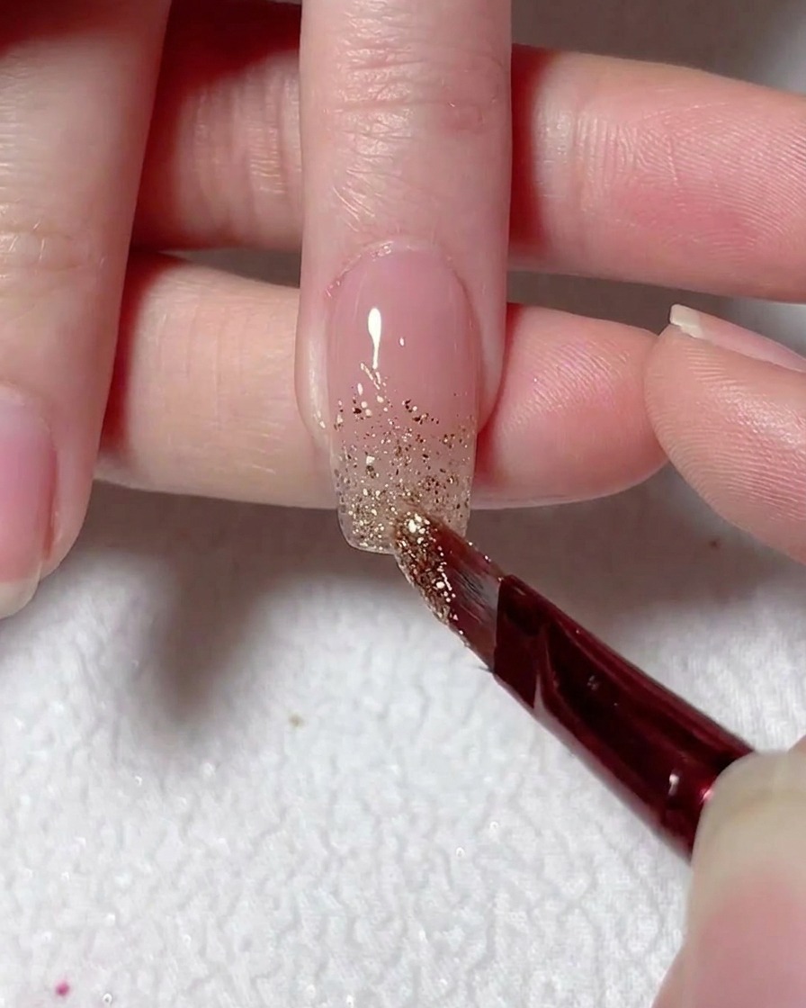 A fine brush blending silver glitter upward from the nail tip to create an ombre effect.